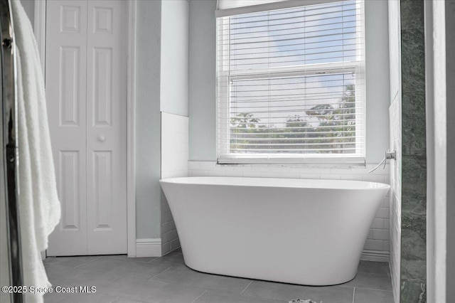 bathroom with a bathing tub, tile walls, and tile patterned floors