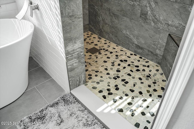 bathroom with tile patterned flooring, a tile shower, and tile walls