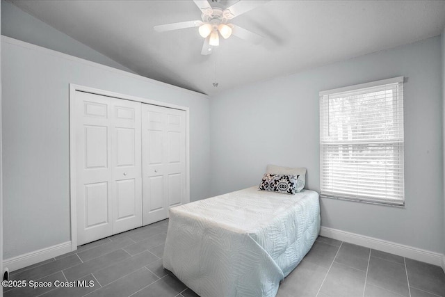 bedroom with ceiling fan, vaulted ceiling, a closet, and dark tile patterned floors