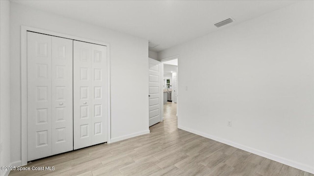 unfurnished bedroom with light wood-type flooring, a closet, visible vents, and baseboards