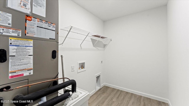 laundry room featuring laundry area, baseboards, wood finished floors, heating unit, and washer hookup