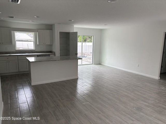 kitchen with light stone counters, baseboards, open floor plan, and wood finished floors