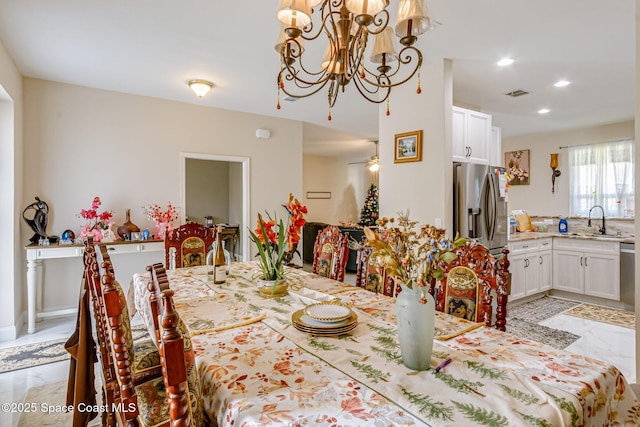 dining room featuring sink and ceiling fan with notable chandelier