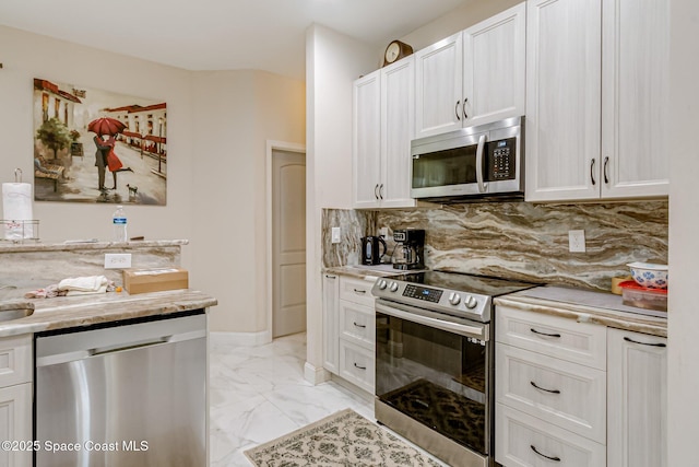 kitchen with white cabinetry, appliances with stainless steel finishes, light stone counters, and tasteful backsplash