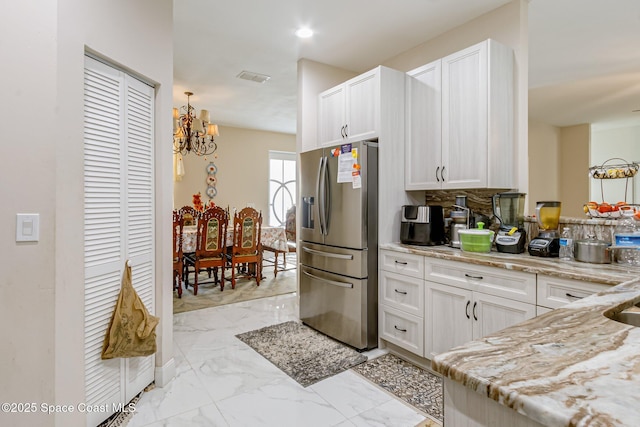 kitchen with backsplash, light stone countertops, stainless steel fridge with ice dispenser, and white cabinets