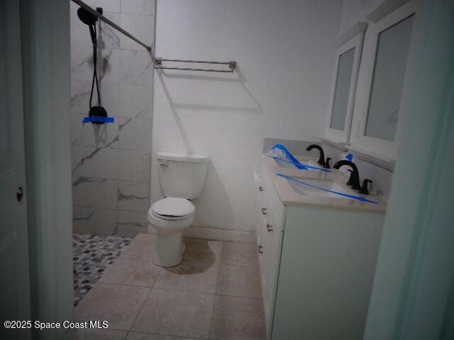 bathroom featuring tiled shower, vanity, toilet, and tile patterned flooring