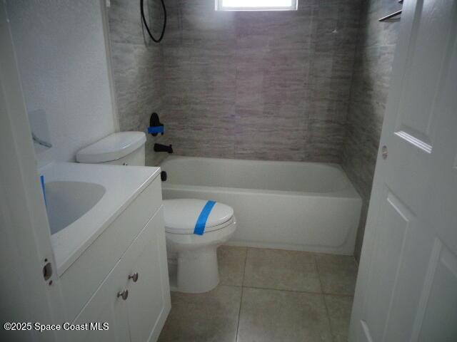 full bathroom with tile patterned flooring, vanity, tiled shower / bath combo, and toilet