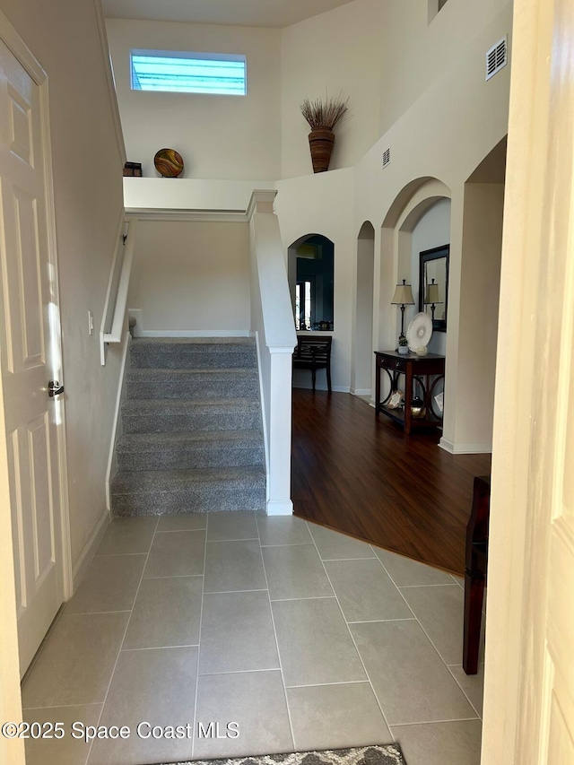 staircase with tile patterned floors and a high ceiling