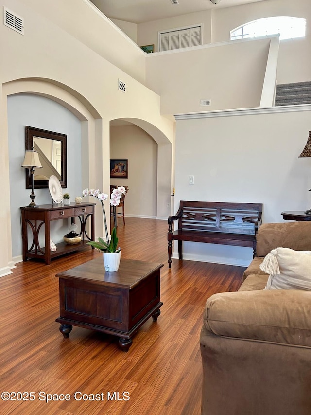 living room with hardwood / wood-style floors and a towering ceiling