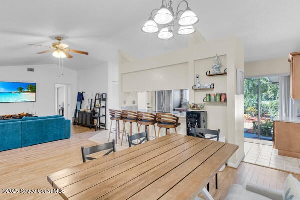 dining space featuring vaulted ceiling, ceiling fan with notable chandelier, and light hardwood / wood-style floors