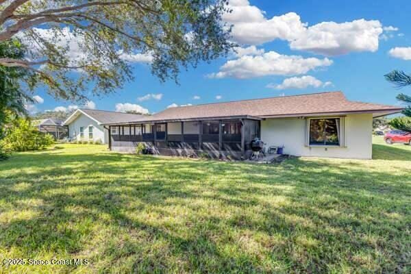 rear view of house with a yard and a sunroom