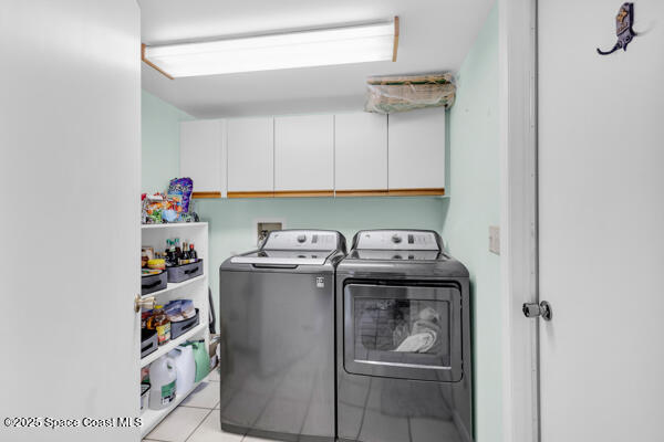 laundry room featuring cabinets, washer and clothes dryer, and light tile patterned floors