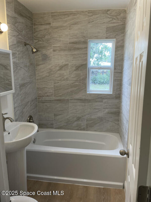 bathroom with hardwood / wood-style floors and tiled shower / bath combo