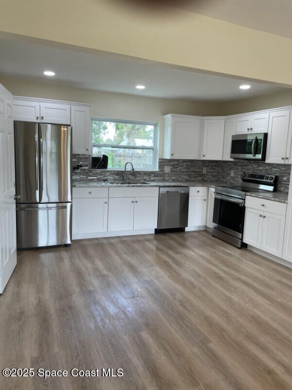 kitchen with sink, backsplash, white cabinets, and appliances with stainless steel finishes