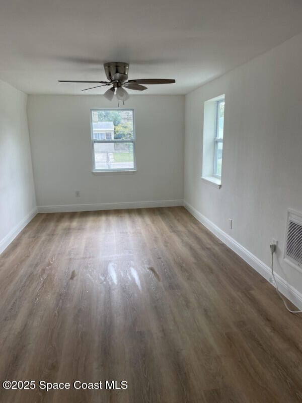 empty room featuring plenty of natural light, dark hardwood / wood-style floors, and ceiling fan