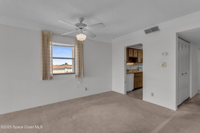 carpeted spare room featuring sink, a textured ceiling, and ceiling fan