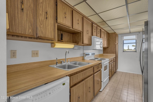 kitchen featuring sink, light tile patterned floors, a drop ceiling, and white appliances