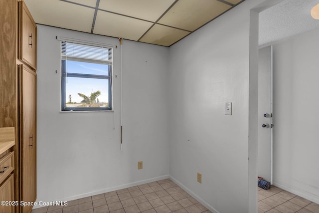 unfurnished room with light tile patterned floors and a drop ceiling