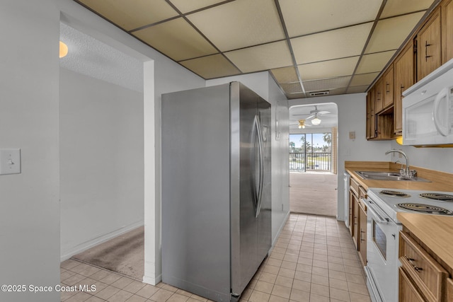 kitchen with light tile patterned flooring, white appliances, a paneled ceiling, and sink