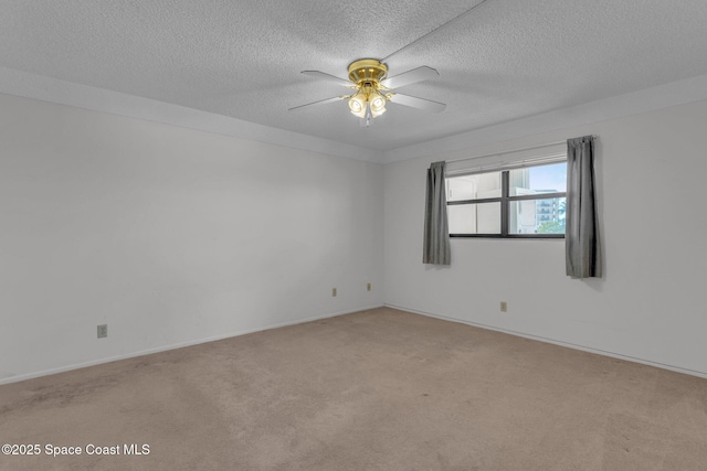 empty room featuring ceiling fan, light colored carpet, and a textured ceiling