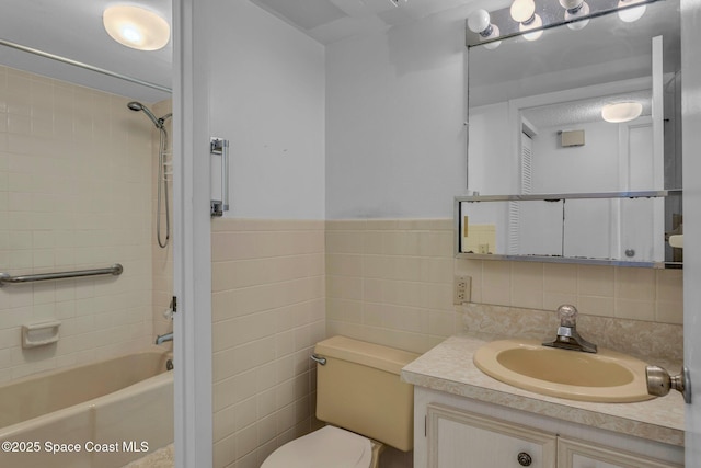 full bathroom featuring tile walls, tiled shower / bath, vanity, and toilet