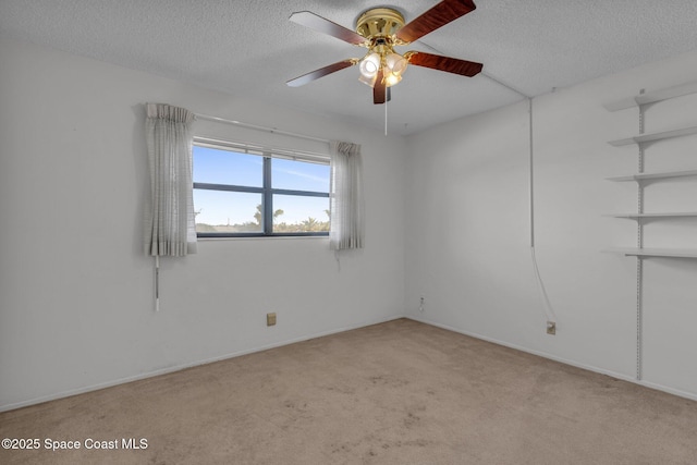 empty room with ceiling fan, light carpet, and a textured ceiling