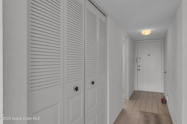 hallway featuring light tile patterned floors and a textured ceiling