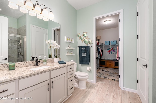 bathroom featuring wood-type flooring, vanity, an enclosed shower, a textured ceiling, and toilet