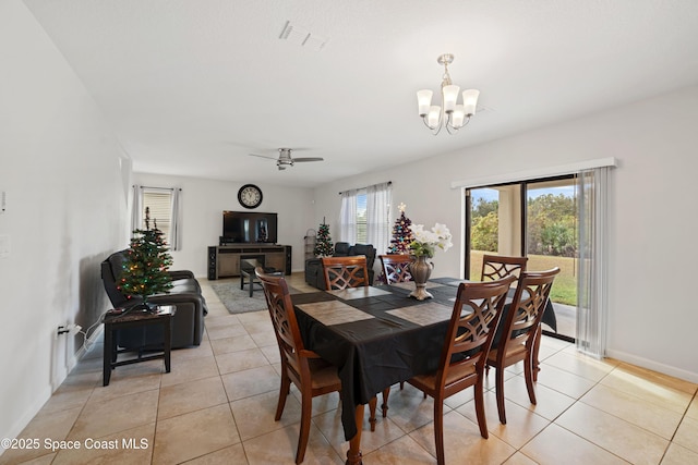 tiled dining space featuring ceiling fan with notable chandelier