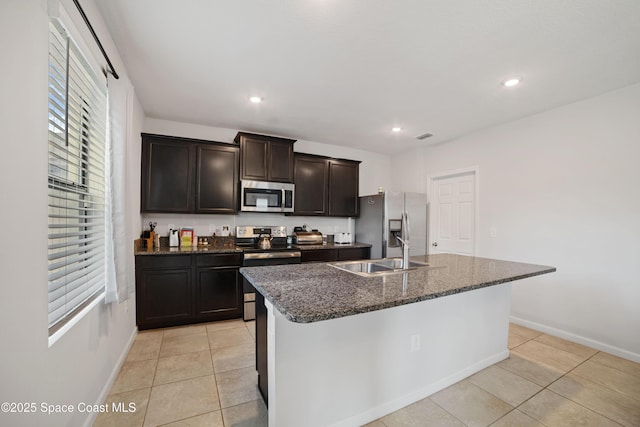 kitchen featuring stainless steel appliances, plenty of natural light, sink, and a center island with sink