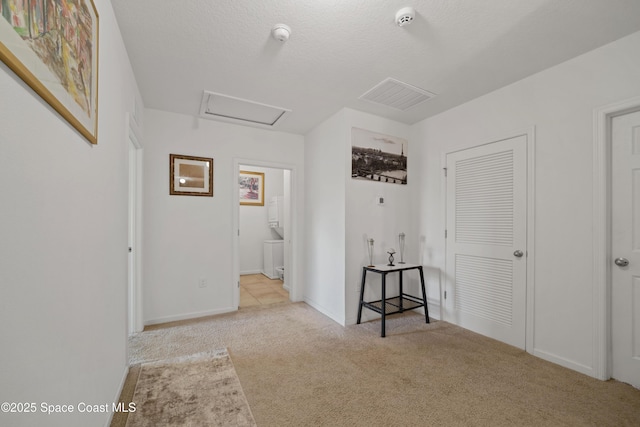 corridor with light colored carpet and a textured ceiling