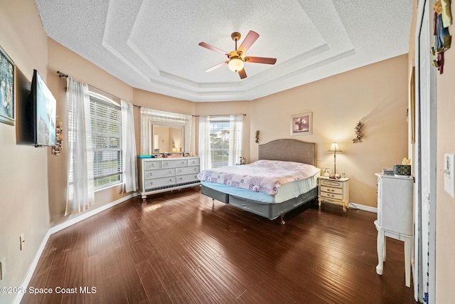 bedroom with dark hardwood / wood-style flooring, a raised ceiling, and a textured ceiling