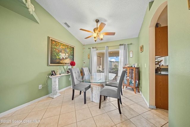 dining room with vaulted ceiling, light tile patterned flooring, ceiling fan, and a textured ceiling