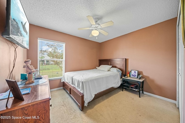 bedroom featuring ceiling fan, light carpet, and a textured ceiling