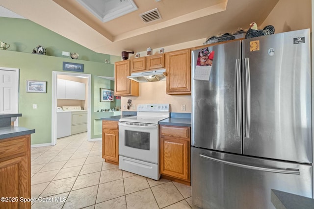 kitchen with light tile patterned flooring, washer and dryer, stainless steel refrigerator, white electric stove, and a tray ceiling