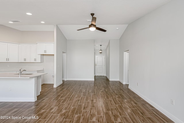 kitchen with dark wood-type flooring, sink, white cabinetry, vaulted ceiling, and ceiling fan