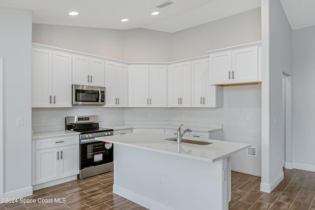 kitchen with an island with sink, appliances with stainless steel finishes, sink, and white cabinets