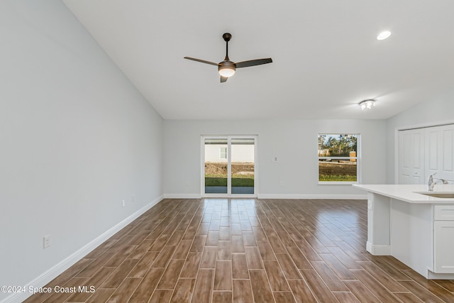 unfurnished living room with hardwood / wood-style flooring, lofted ceiling, sink, and ceiling fan