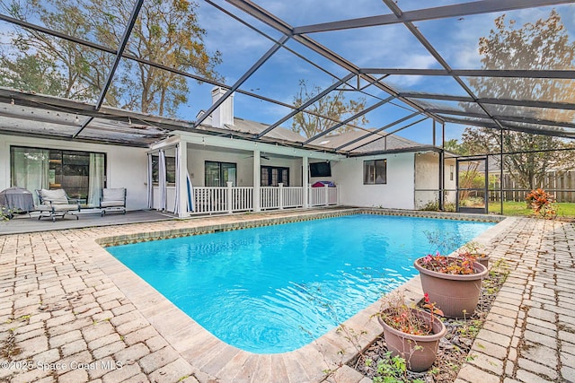 view of swimming pool featuring a patio, ceiling fan, and glass enclosure