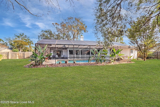 back of property featuring a yard, a lanai, and a fenced in pool