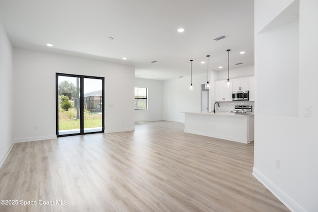 unfurnished living room with sink and light hardwood / wood-style floors