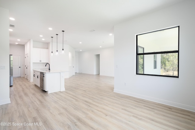 kitchen featuring stainless steel appliances, a kitchen island with sink, white cabinets, and decorative light fixtures