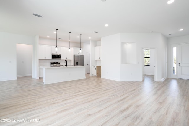 unfurnished living room with sink and light hardwood / wood-style floors