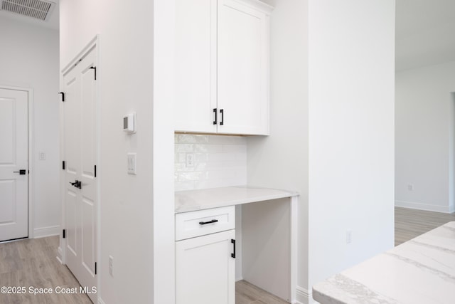 bar featuring white cabinetry, light stone countertops, backsplash, and light hardwood / wood-style floors