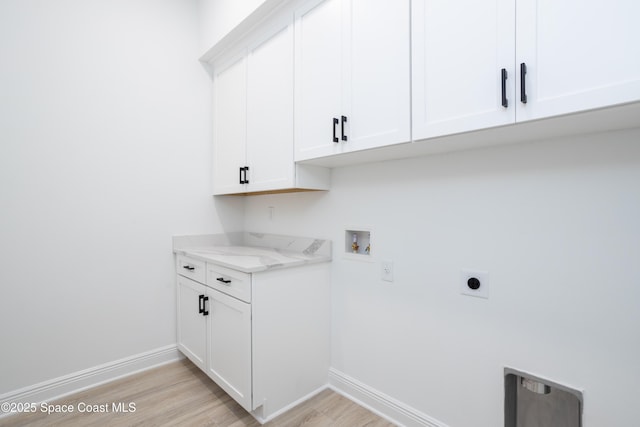 clothes washing area with cabinets, hookup for a washing machine, hookup for an electric dryer, and light hardwood / wood-style floors