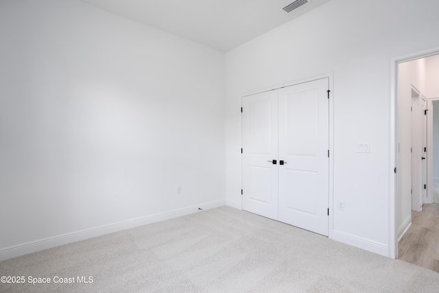 unfurnished bedroom with light colored carpet and a closet