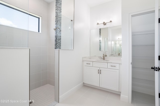 bathroom featuring a tile shower, vanity, and tile patterned flooring