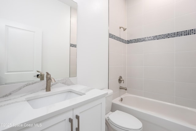 full bathroom featuring tiled shower / bath, vanity, and toilet