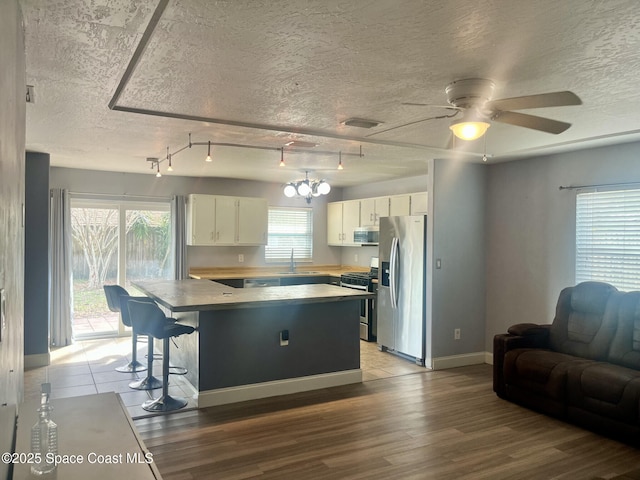 kitchen with sink, a textured ceiling, light wood-type flooring, stainless steel appliances, and white cabinets