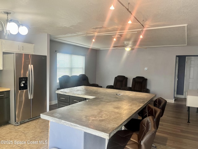 kitchen featuring light wood-type flooring, a textured ceiling, ceiling fan, and stainless steel fridge with ice dispenser